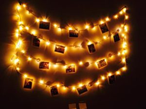 LED lights hanging on a bedroom wall with pictures of friends 