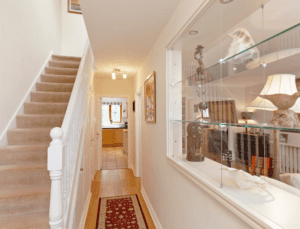 a family home hallway with carpet stairs and a red rug on the floor, with a white walls