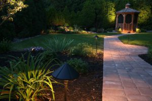 dark winter evening in a well lit garden, with a path leading down to a gazebo