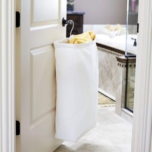 white laundry basket hanging off the back of a door