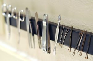 magnetic strip installed in a bathroom, holding items such as nail clipper, tweezers, hairpins and scissors