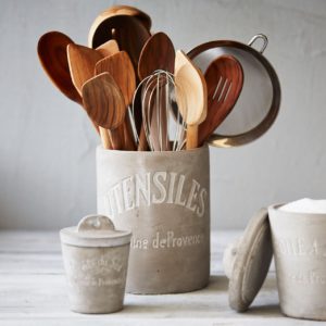 spatulas and other kitchen utensils stored ina utensil holder in a white kitchen